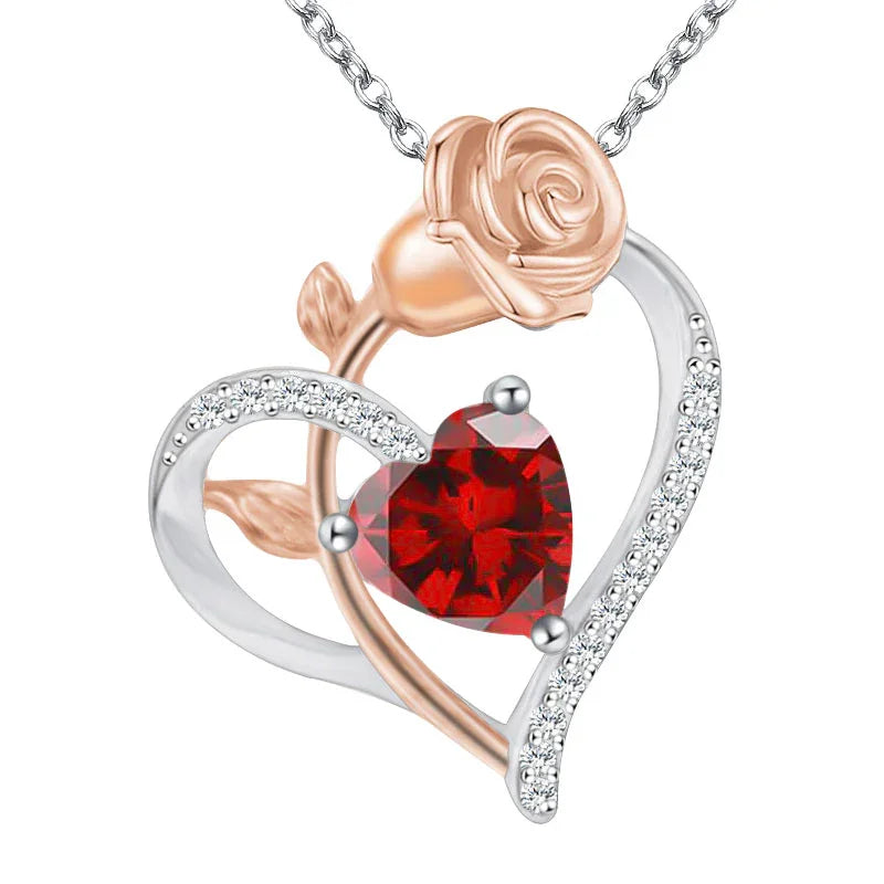Silver and rose gold heart-shaped pendant featuring a rose design with a central red heart-shaped gemstone and sparkling crystal accents, displayed on a white background.