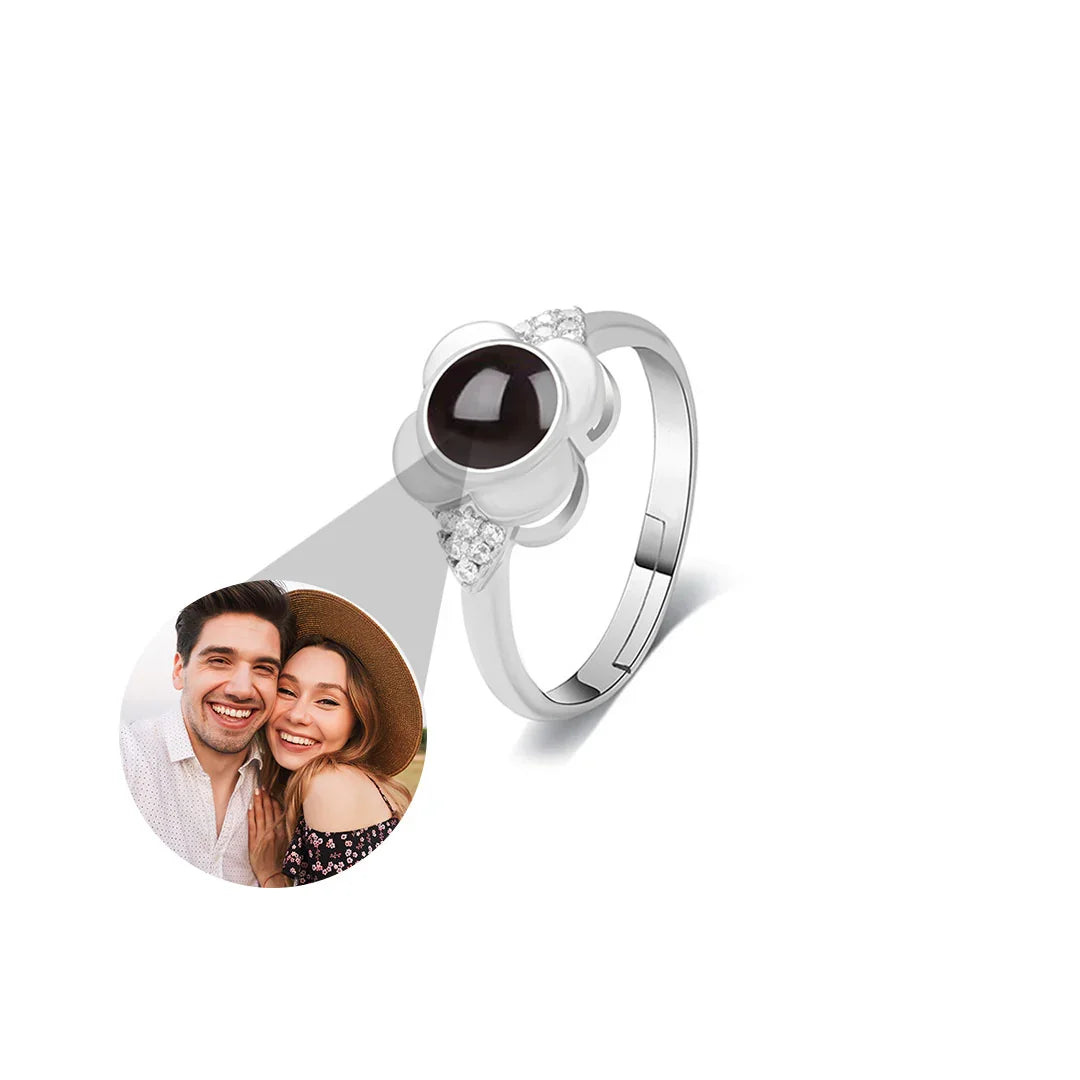 Silver ring with a dark gemstone and a small round photo of a couple on a white background