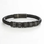 A men’s bracelet with a black braided leather strap and multiple round black beads evenly spaced along the band. Each bead features engraved lettering and is separated by thin metallic spacer rings. The bracelet has a sturdy magnetic clasp with a matte finish.