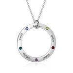A sterling silver circle pendant necklace engraved with names and adorned with colorful birthstones on a delicate chain.