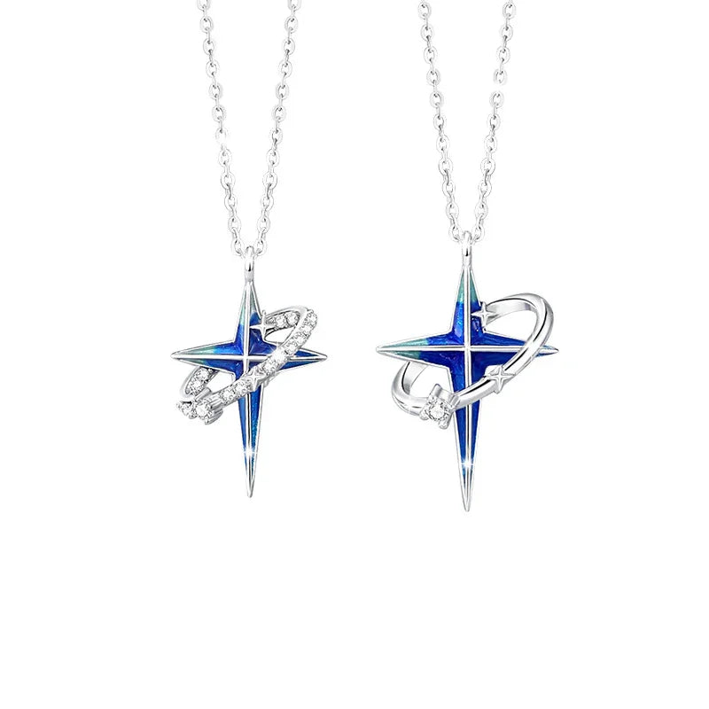 A pair of silver couple necklaces featuring blue star pendants with orbit ring designs — one with sparkling stones on the ring and the other with a smooth silver ring, displayed on a white background.