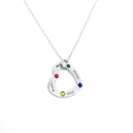 A silver heart-shaped necklace pendant with colorful gemstones and engraved names including Mayra, Daniel, and Alexis, displayed on a white background
