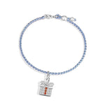 A delicate Christmas-themed bracelet featuring a braided light blue cord, accented with small silver beads, and a festive gift box charm adorned with sparkling clear stones and a vertical row of red gems.