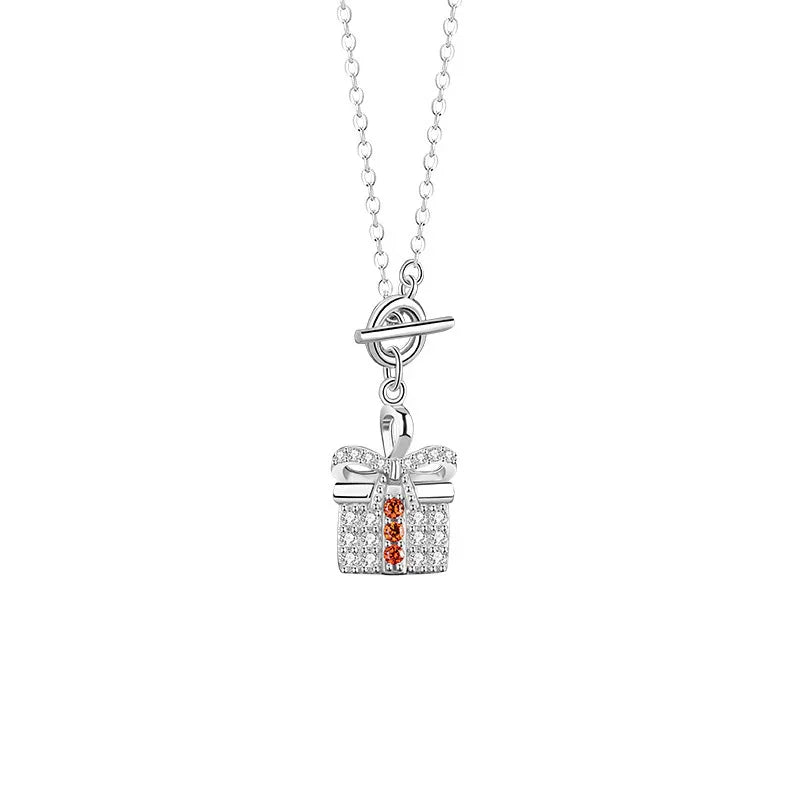 A silver necklace featuring a pendant shaped like a gift box, adorned with sparkling zircon stones and a bow detail, with three orange zircon accents in the center.