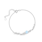 Delicate silver bracelet with star and zircon details featuring a central blue gemstone on a white background.
