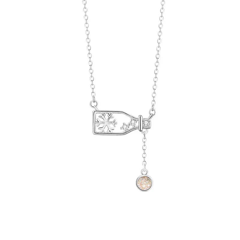 Delicate silver necklace with a snowflake bottle charm and a small sparkling pendant on a white background.