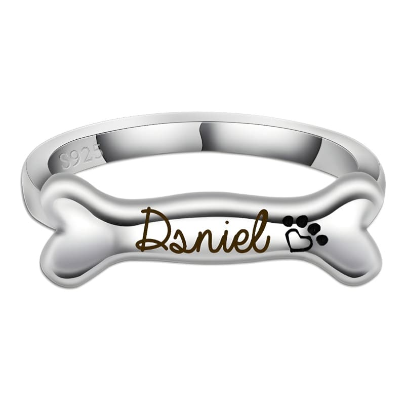 Silver bone-shaped ring with 'Dsniel' engraving on a white background