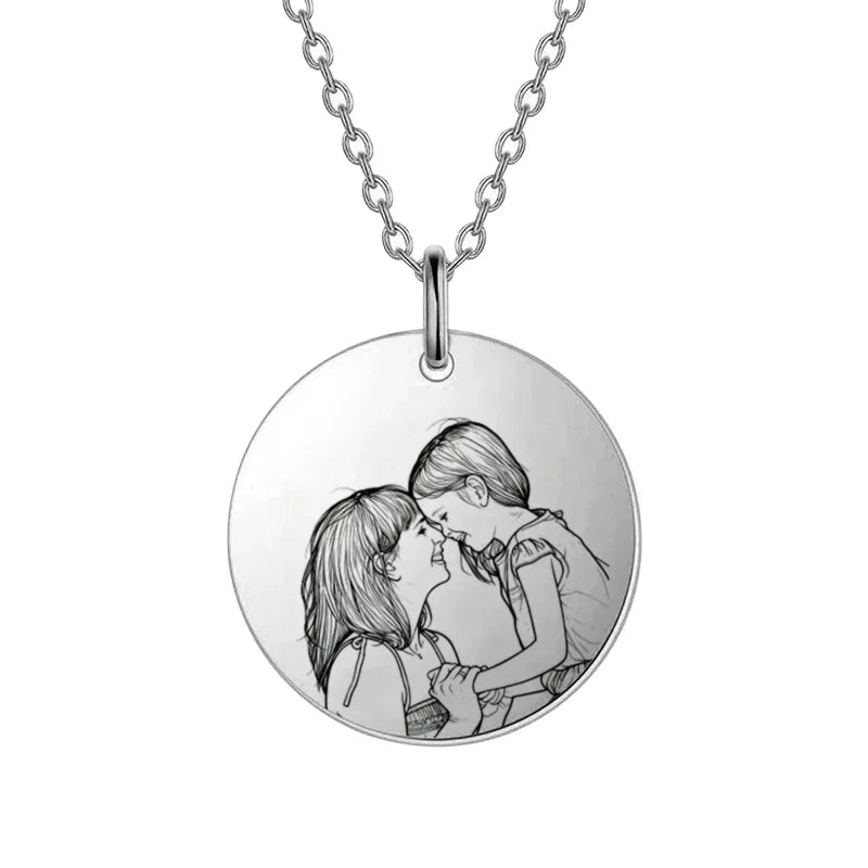 Silver necklace with a round pendant featuring an engraved illustration of two people embracing.