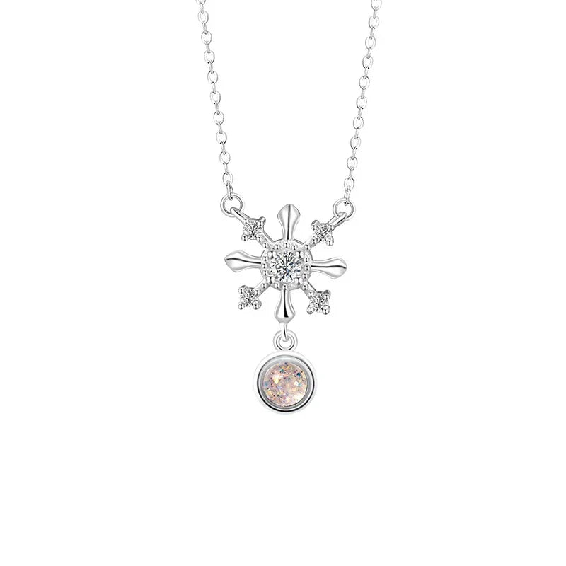 A delicate silver necklace featuring a snowflake-shaped pendant with sparkling crystal details and a round shimmering glaze stone drop, displayed on a white background.