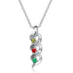 A personalized silver necklace featuring a twisting pendant with three engraved names — “Huston,” “Hayden,” and “Ileana” — each paired with a colorful gemstone in yellow, red, and green, symbolizing birthstones.