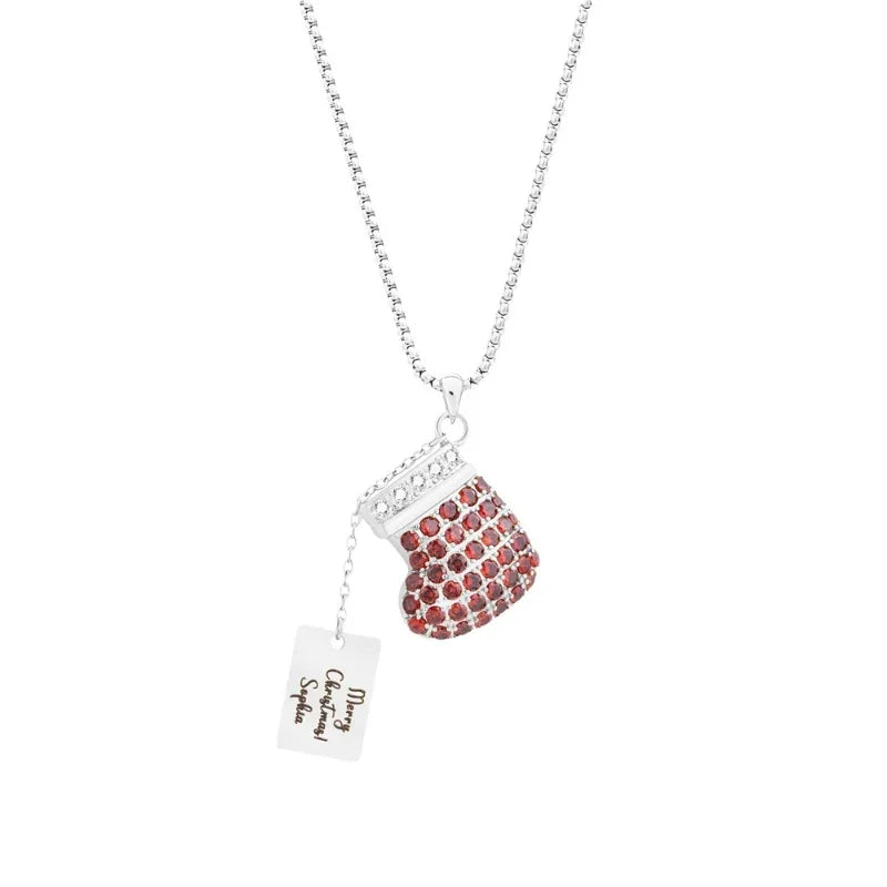 A festive necklace featuring a sparkling red Christmas stocking pendant adorned with gemstones and a small engraved tag that reads “Merry Christmas! Sophia,” hanging from a silver chain.