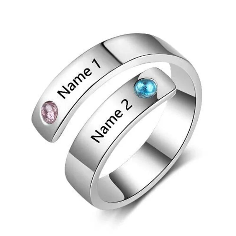 Silver wrap-style ring with two engraved names and two colorful birthstones, representing love and connection.