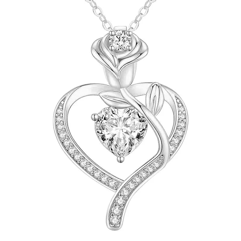 Silver heart-shaped pendant featuring a rose design with a central heart-cut gemstone and sparkling crystal accents, displayed on a white background.