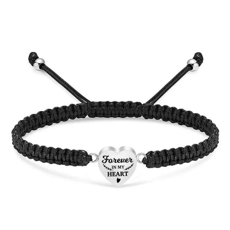 Black braided bracelet with a silver heart-shaped charm on a white background