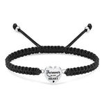 Black braided bracelet with a silver heart-shaped charm on a white background