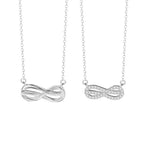 A pair of silver couple necklaces featuring infinity symbols — one with a sleek polished design and the other adorned with sparkling stones, displayed side by side on a white background.