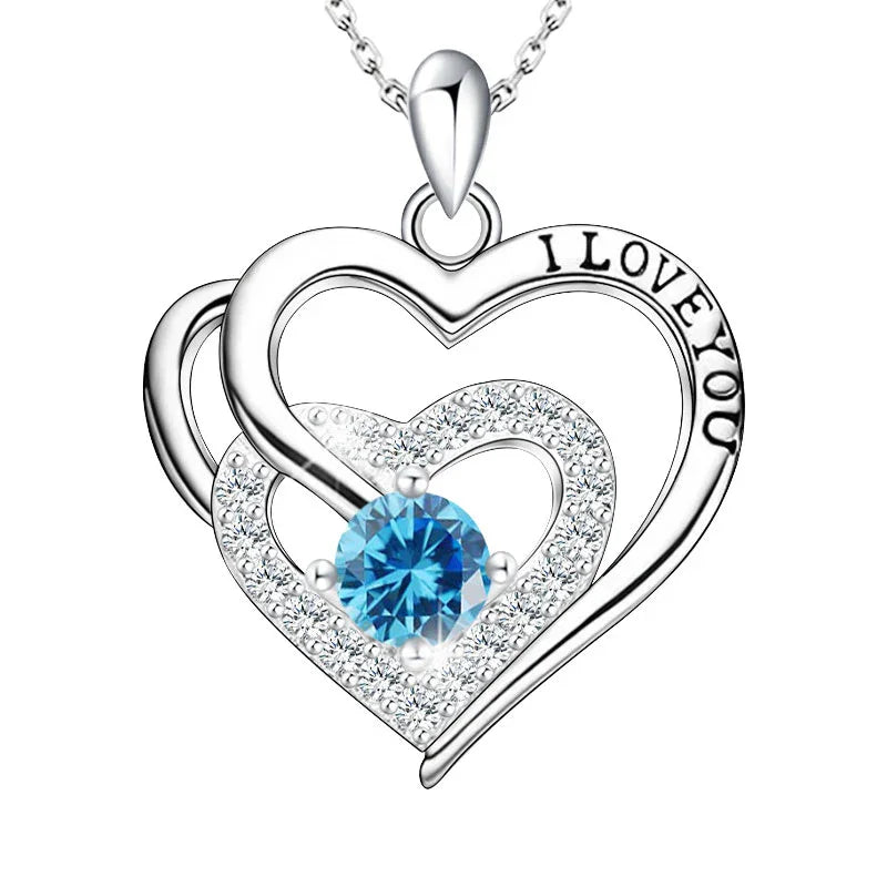 Silver heart-shaped pendant with blue gemstone and 'I LOVE YOU' engraving on a white background