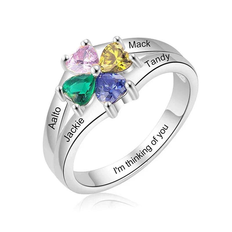 Silver ring with four heart-shaped birthstones and engraved names.