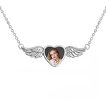 Silver necklace with heart-shaped pendant featuring a photo of a woman, surrounded by angel wings on a white background.
