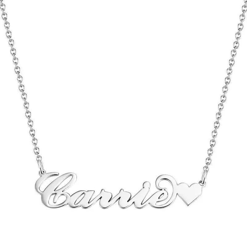 A personalized silver necklace featuring the name “Carrie” in elegant cursive script, ending with a small heart design on the right side. The pendant is attached to a delicate silver chain, showcasing a sleek and polished finish against a white background.