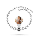 Silver bracelet with heart-shaped charm featuring a photo of a couple on a white background