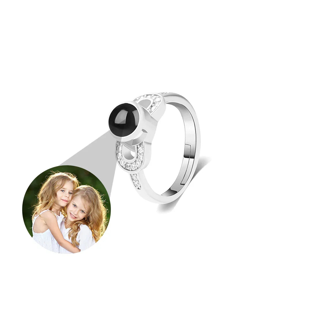 Silver ring with a black gemstone and heart design, featuring a photo of two children on a white background.