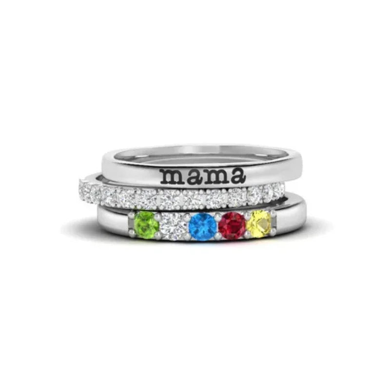 Stacked silver rings with colorful birthstones and a top band engraved with 'mama'.