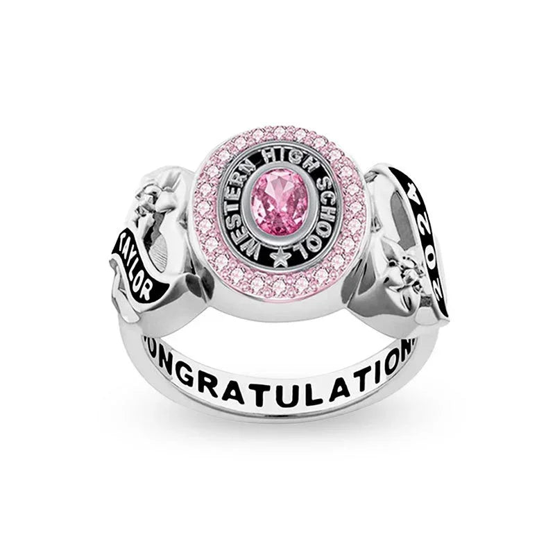 Silver class ring with a pink center stone and engraved details.