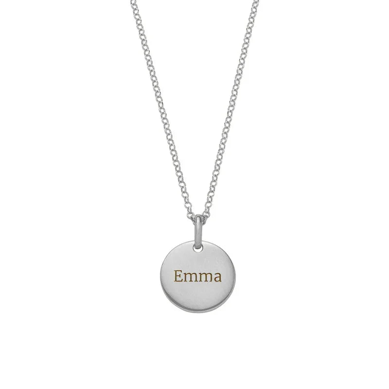 A minimalist silver necklace featuring a circular pendant engraved with the name “Emma,” hanging from a fine silver chain against a plain white background.