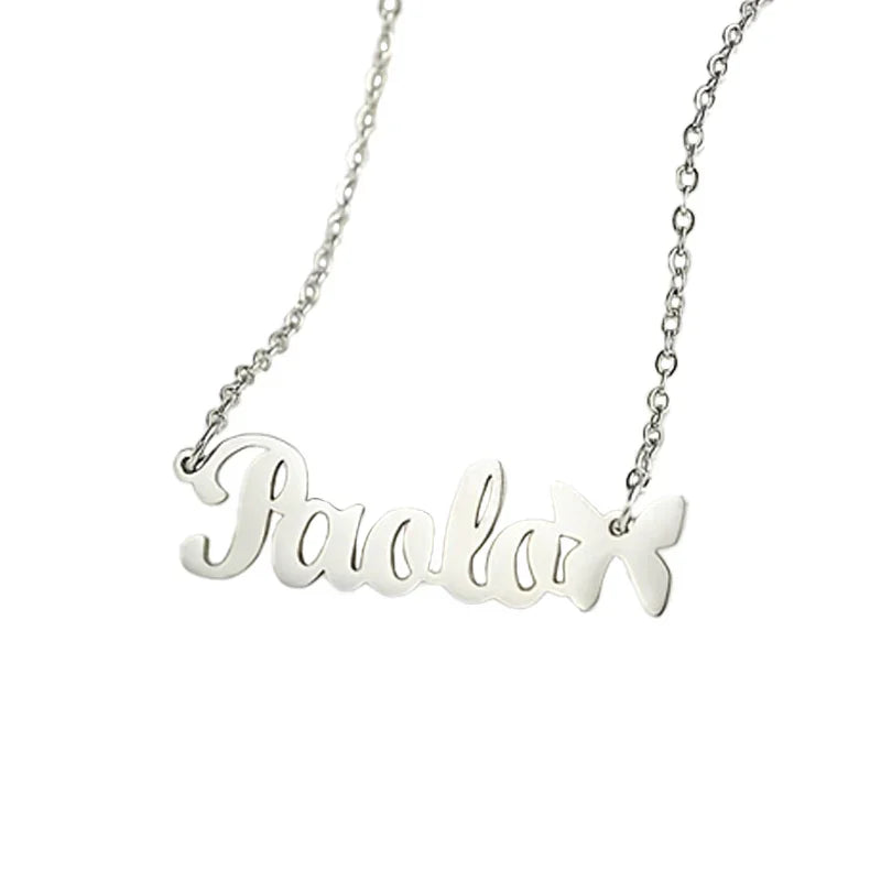 A personalized silver necklace featuring the name “Paola” in smooth cursive font, accented with a small butterfly charm at the end of the name, attached to a delicate chain.