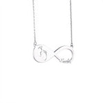 A silver infinity necklace with a delicate pendant featuring baby footprint cutouts on one side and a customized name “Candy” on the other. The pendant is attached to a fine silver chain, symbolizing love and connection.
