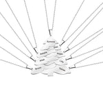 Silver Christmas tree-shaped pendant necklace composed of multiple interlocking layers, each engraved with different names, displayed on a white background.