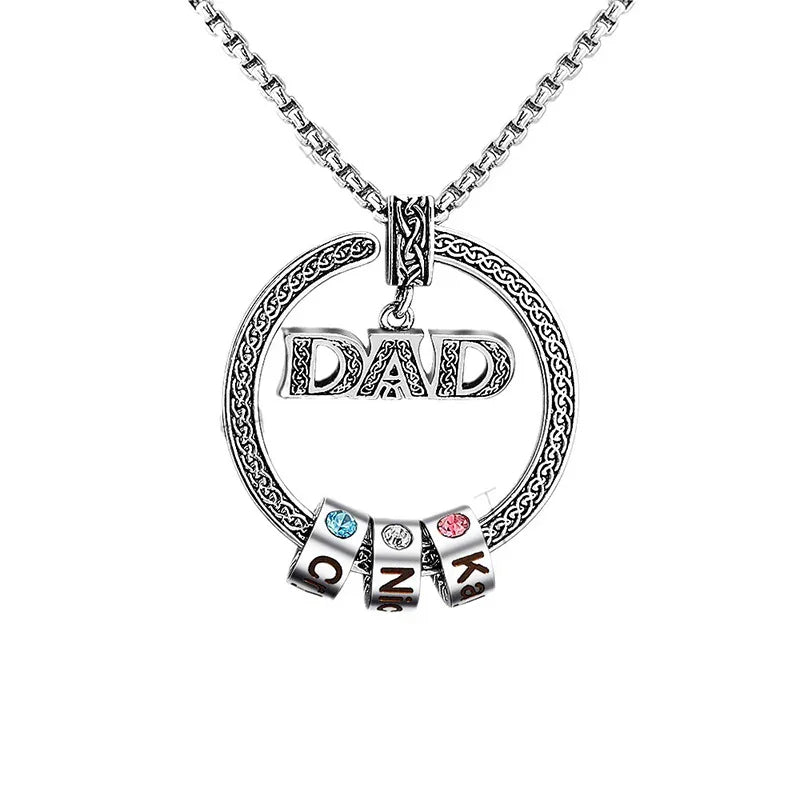 A stainless steel necklace featuring a circular pendant with the engraved word “DAD” at the center, accented by three customizable name beads, each set with a colorful birthstone to represent family members.