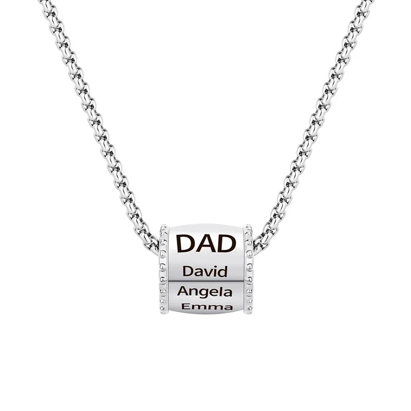 Close-up image of a men’s necklace featuring a polished cylindrical pendant engraved with “DAD” and three names — David, Angela, and Emma — on a stainless steel chain.