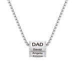 Close-up image of a men’s necklace featuring a polished cylindrical pendant engraved with “DAD” and three names — David, Angela, and Emma — on a stainless steel chain.