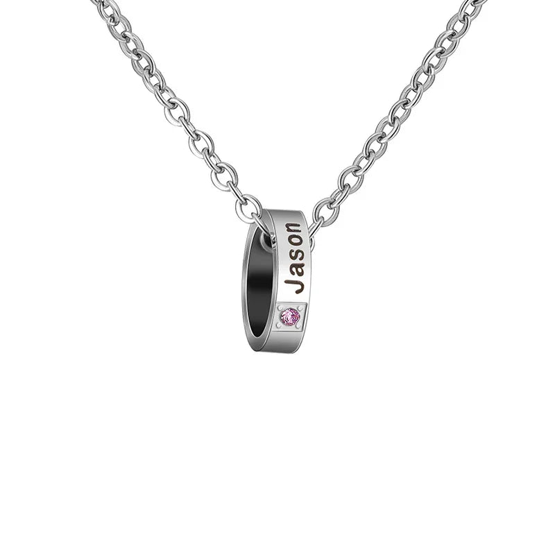 A stainless steel necklace featuring a circular pendant engraved with the name “Jason” and accented by a small pink birthstone, symbolizing personalization and elegance.