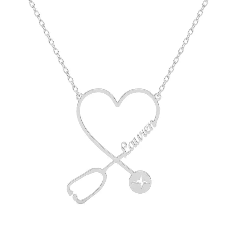A silver personalized name necklace featuring a heart-shaped design intertwined with a stethoscope and the name “Lauren” in elegant script. The stethoscope’s chest piece includes a small engraved heartbeat line, symbolizing care and compassion.