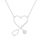 A silver personalized name necklace featuring a heart-shaped design intertwined with a stethoscope and the name “Lauren” in elegant script. The stethoscope’s chest piece includes a small engraved heartbeat line, symbolizing care and compassion.