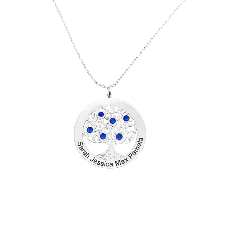 A silver Tree of Life necklace featuring a circular pendant engraved with the names “Sarah,” “Jessica,” “Max,” and “Pamela.” The pendant’s intricate tree design is adorned with multiple blue gemstones, hanging from a delicate silver chain against a plain white background.