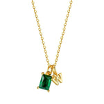 Gold necklace with a green gemstone pendant on a white background
