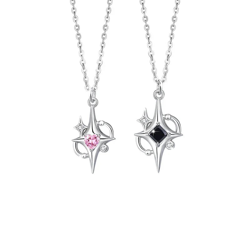 A pair of silver couple necklaces featuring star-shaped pendants — one with a pink heart gemstone and the other with a black square gemstone, both accented with small sparkling stones, displayed on a white background.