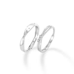 A pair of elegant silver couple rings displayed on a white background. The left ring features a smooth, slightly twisted band with small star-like stones, while the right ring has a delicate crisscross design adorned with sparkling gemstones in the center, creating a romantic and refined look.