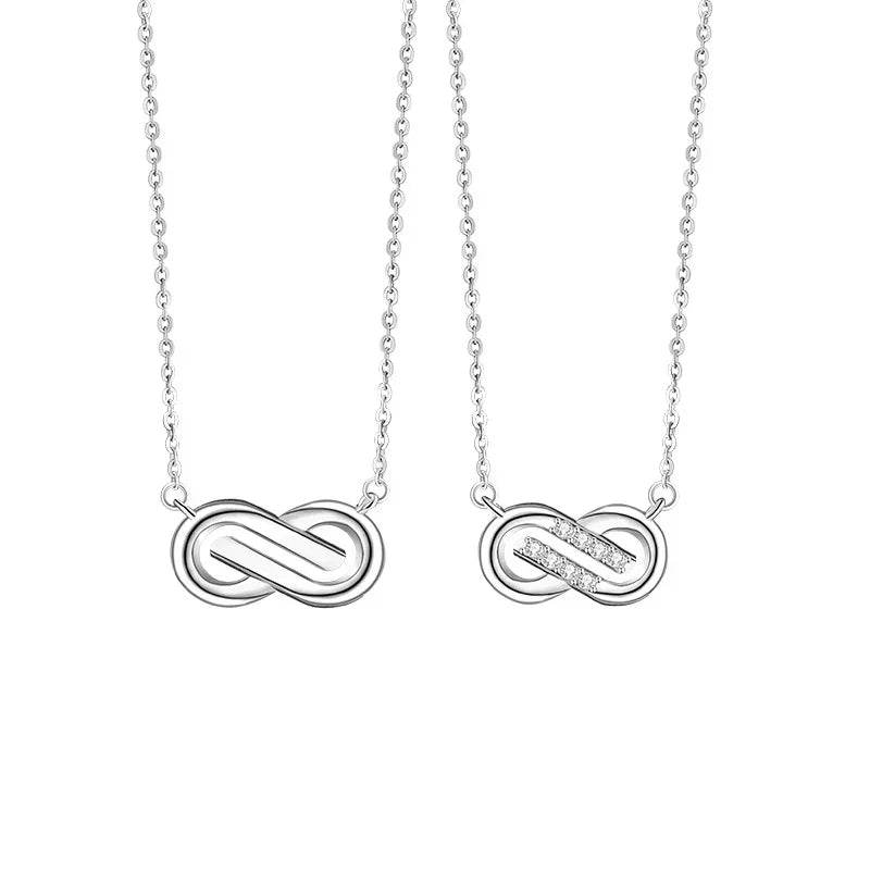 A pair of silver couple necklaces featuring Möbius loop pendants — one with a sleek polished finish and the other accented with small sparkling stones, displayed on a white background.