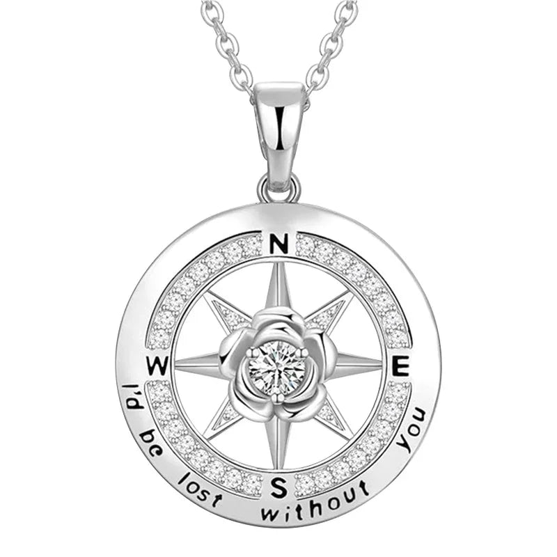 A silver compass-shaped necklace engraved with “I’d be lost without you,” featuring a central flower and sparkling crystals, symbolizing love as one’s true direction.