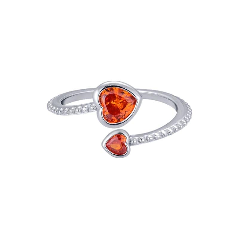 Silver ring with two heart-shaped orange gemstones on a white background