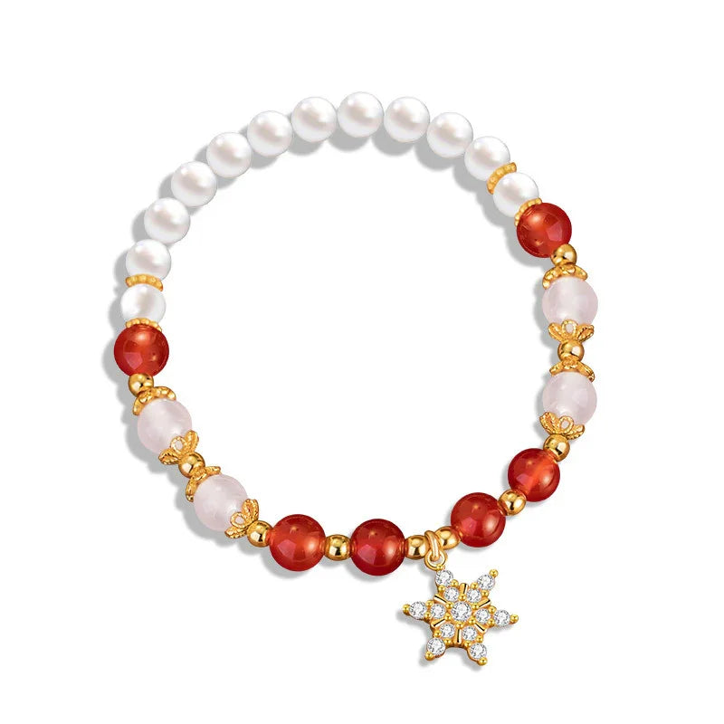 A festive Christmas-themed bracelet featuring alternating white pearls, red and pink beads, and gold spacer accents, completed with a sparkling snowflake charm encrusted with clear stones.